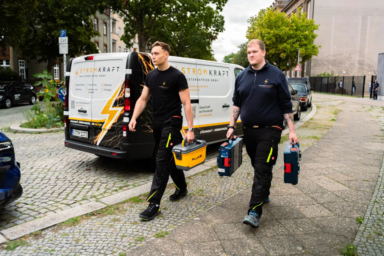 Zwei Kollegen von Stromkraft mit Werkzeugkoffern auf dem Weg zum Einsatz